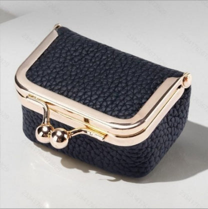 Compact genuine leather mini jewelry case with gold-tone clasp and textured black exterior for travel storage.