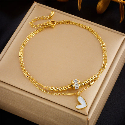 Gold double layer fashion jewelry ankle chain with love heart charm and tassel on a beige box