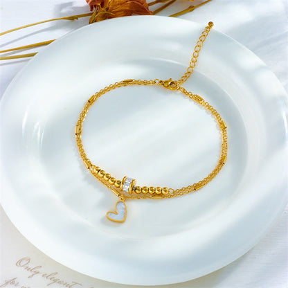 Gold fashion jewelry ankle chain with double layers and heart charm on white plate