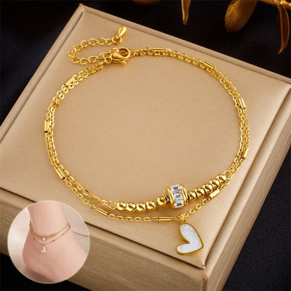 Gold double layer fashion jewelry anklet with heart charm and tassel detail on foot for women party accessories